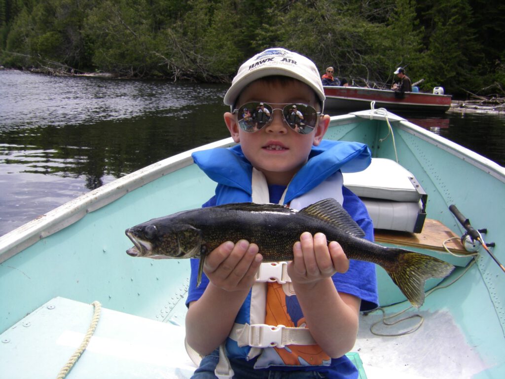 A little boy shows off the trout he caught at Goat camp.