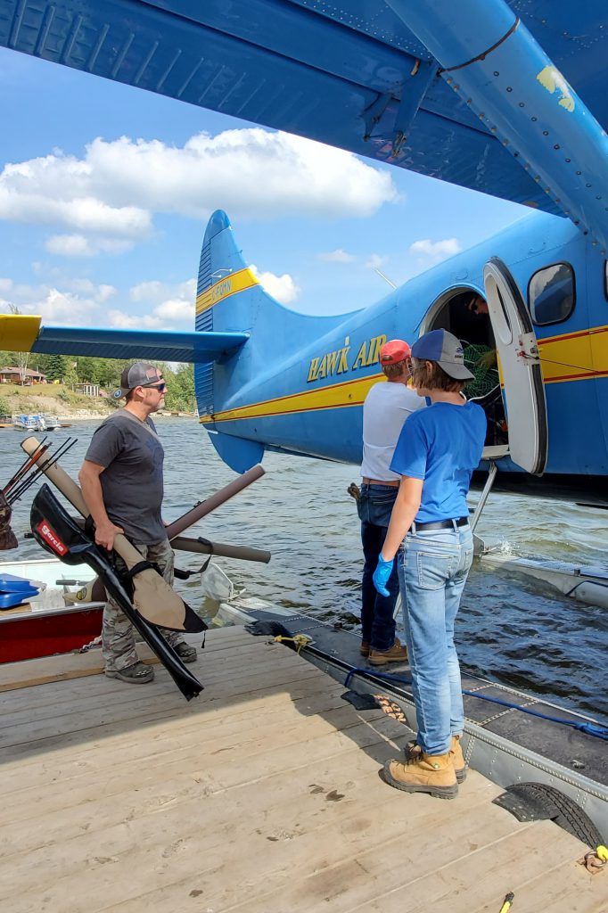 People loading fishing gear onto a plane.
